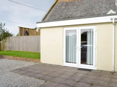 a white house with a sliding glass door at Lindum Leys in Saint Hilary