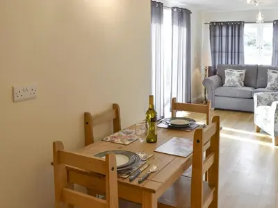 a dining room table with a bottle of wine on it at Lindum Leys in Saint Hilary