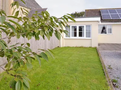 a house with a fence and a green yard at Lindum Leys in Saint Hilary