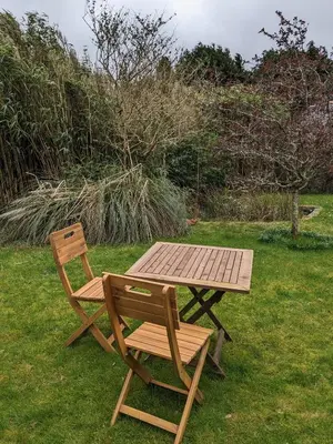 a picnic table and a chair next to a wooden table and bench at The Cottage, Little Trembroath in Stithians