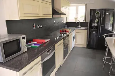 a kitchen with white cabinets and a black refrigerator at Bonython Farmhouse in Cury