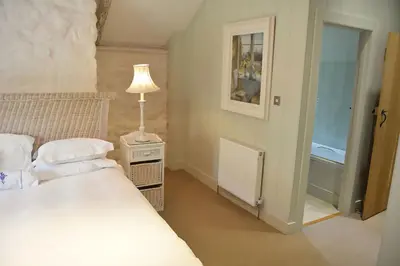 a bedroom with a bed and a lamp on a night stand at Bonython Farmhouse in Cury