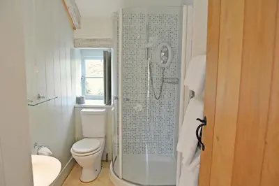 a white bathroom with a toilet and a shower at Bonython Farmhouse in Cury