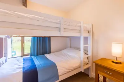 a bedroom with two bunk beds and a desk at Cargurra Park Farm in Boscastle