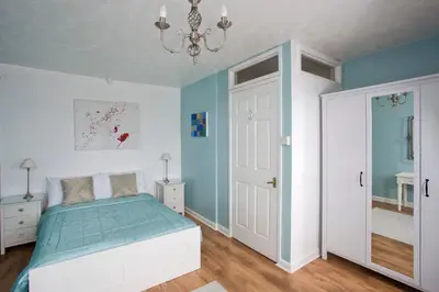 a bedroom with a bed with blue walls and a chandelier at The Old Farmhouse at Mena in Bodmin