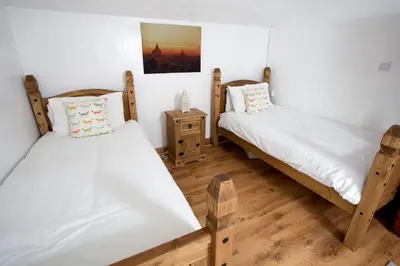 two twin beds in a room with wooden floors at The Old Farmhouse at Mena in Bodmin