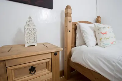 a bedroom with a wooden bed and a wooden night stand at The Old Farmhouse at Mena in Bodmin