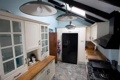 a kitchen with white cabinets and a black refrigerator at The Old Farmhouse at Mena in Bodmin