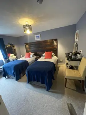 a bedroom with two beds and a desk and a chair at Skyline Guesthouse in Newquay