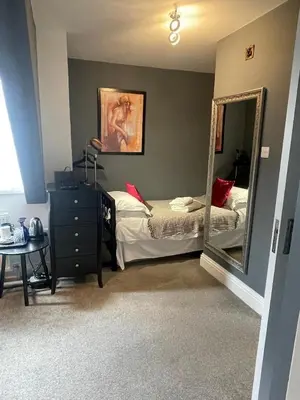 a bedroom with a mirror and a bed and a dresser at Skyline Guesthouse in Newquay