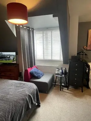 a bedroom with a bed and a chair and a window at Skyline Guesthouse in Newquay