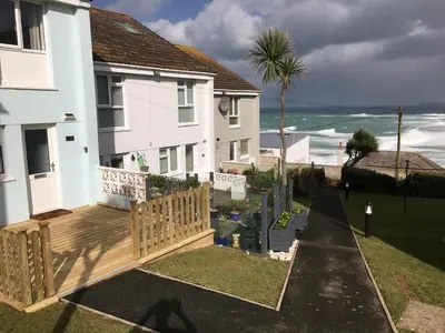 a house with a deck with the ocean in the background at 34 Surfview Beach House in Newquay