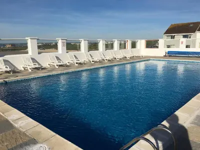 a swimming pool with chaise lounges and chairs at 34 Surfview Beach House in Newquay