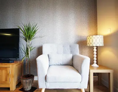 a white chair in a living room with a lamp at Ocean Views 3 in Newquay
