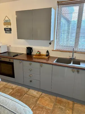 a kitchen with white cabinets and a sink at The Haven in Portreath