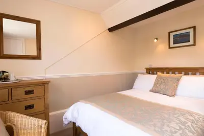 a bedroom with a bed and a mirror and a dresser at Deganwy Hotel in Looe