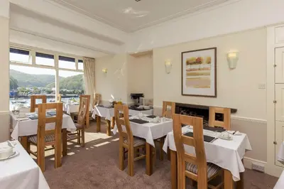 a restaurant with tables and chairs and a fireplace at Deganwy Hotel in Looe
