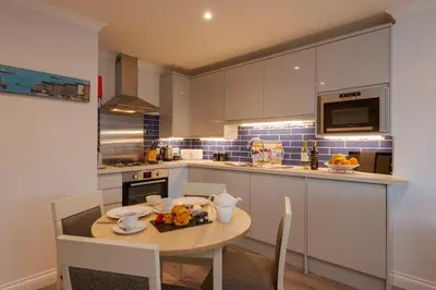 a kitchen with a table with a bowl of fruit on it at Beachcombers Apartments in Newquay