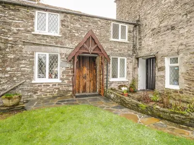 a brick house with a wooden door and a yard at Mill Cottage in Tintagel
