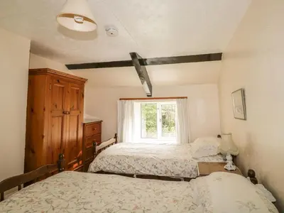 a bedroom with two beds and a window at Mill Cottage in Tintagel