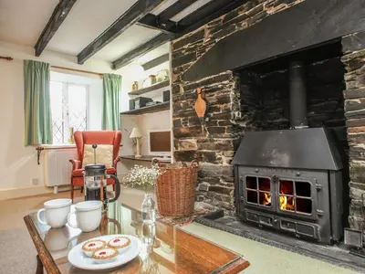 a living room with a stone fireplace and a table at Mill Cottage in Tintagel