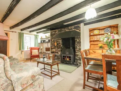 a living room with a stone fireplace and a table at Mill Cottage in Tintagel