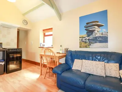 a living room with a blue couch and a table at Cosy Cottage in Liskeard