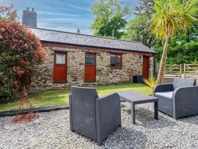 a stone cottage with two chairs and a table at Cosy Cottage in Liskeard
