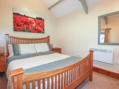 a bedroom with a wooden bed and a painting on the wall at Cosy Cottage in Liskeard