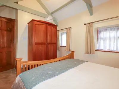 a bedroom with a bed and a wooden cabinet at Cosy Cottage in Liskeard