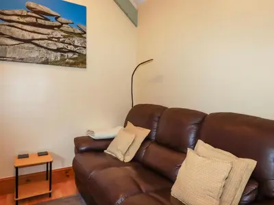 a living room with a brown leather couch at Barn Cottage in Liskeard