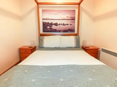 a bedroom with a bed with a painting above it at Barn Cottage in Liskeard