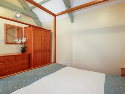 a bedroom with a bed and a wooden dresser at Barn Cottage in Liskeard