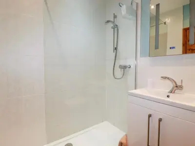 a white bathroom with a shower and a sink at Barn Cottage in Liskeard