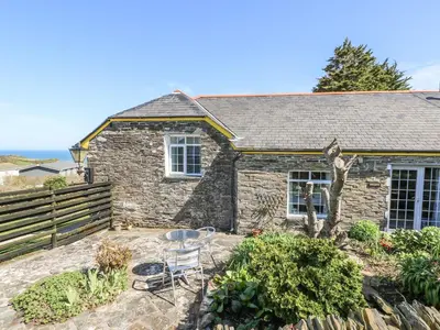 a stone cottage with a table and chairs in front of it at The Garden Apartment in Tintagel