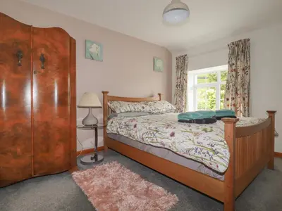 a bedroom with a wooden bed and a window at The Garden Apartment in Tintagel