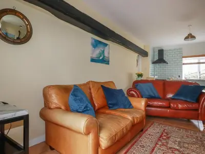 a living room with a leather couch and blue pillows at The Garden Apartment in Tintagel