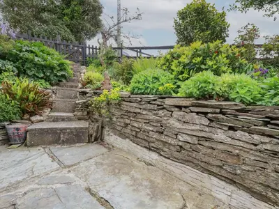 a garden with a stone wall and some plants at The Garden Apartment in Tintagel