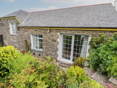 a brick house with white windows and plants at The Garden Apartment in Tintagel
