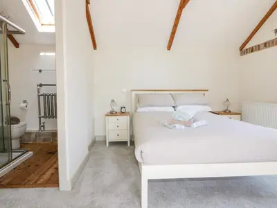 a bedroom with a white bed with a baby on it at The Old Smithy in Saint Columb Major