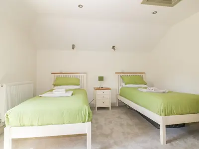 two beds in a room with white walls at The Old Smithy in Saint Columb Major