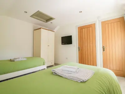 a bedroom with two green beds and a tv at The Old Smithy in Saint Columb Major