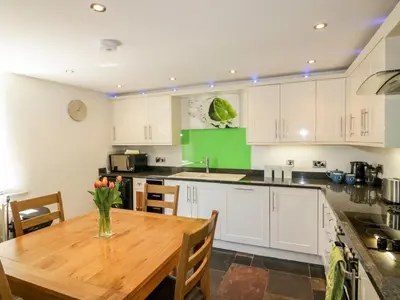 a kitchen with white cabinets and a wooden table at The Old Smithy in Saint Columb Major