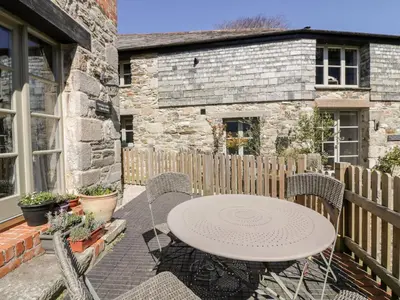 a patio with a table and chairs and a fence at The Old Smithy in Saint Columb Major
