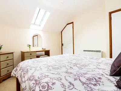 a bedroom with a bed and a dresser and a window at The Shippon in Launceston