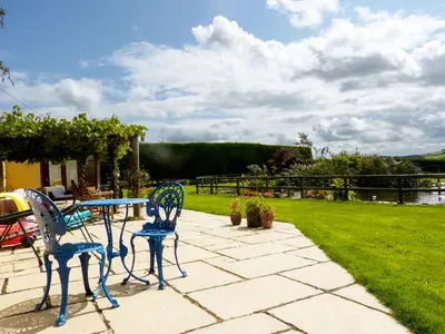 a patio with a table and two chairs and a lawn at The Shippon in Launceston