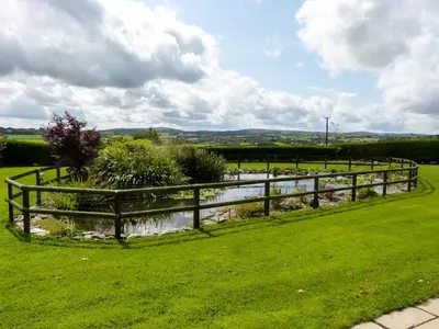 a wooden fence in a field with a river at The Shippon in Launceston