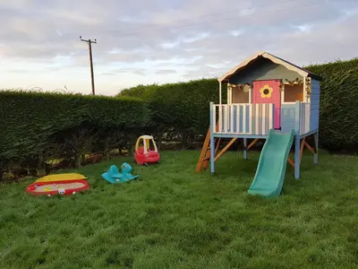 a childs playground with a play set in the grass at The Shippon in Launceston
