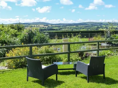 two chairs and a table on a lawn with a view at The Wagon House in Launceston