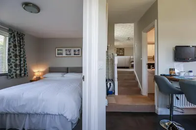 a bedroom with a bed and a desk and a kitchen at Jenny Wren in Par